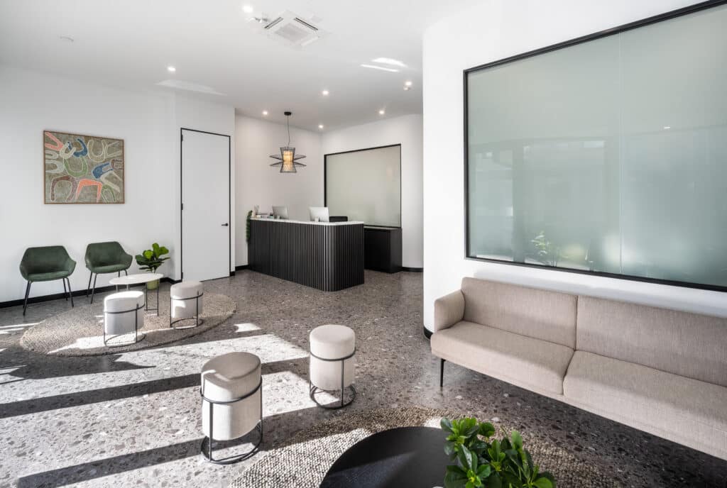 A waiting room/ reception area with a front desk, couch, and scattered additional seating.